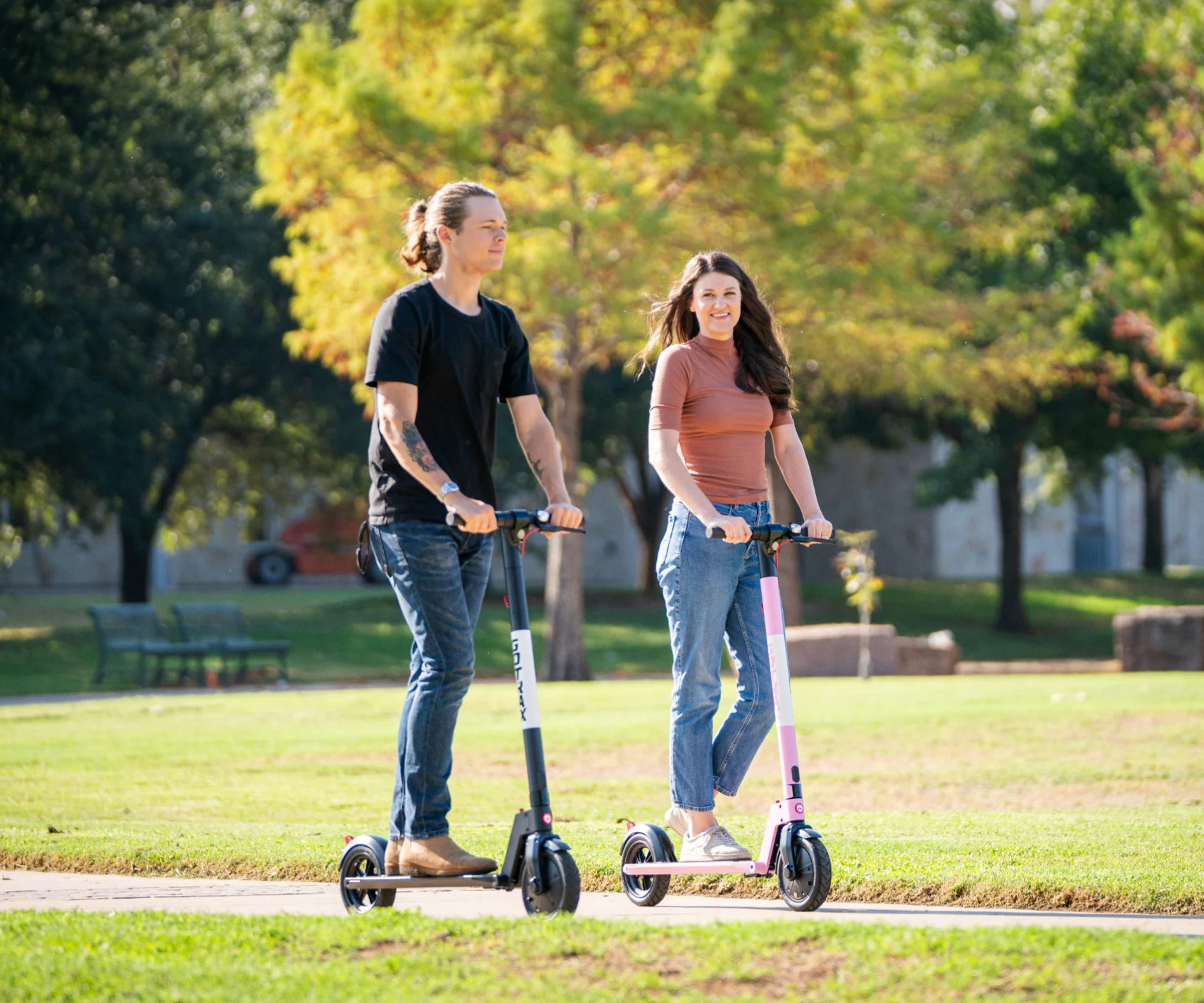 jeune couple se promenant en trottinette electrique Gotrax dans un parc